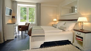 A hotel room with a bed, a chair, a TV, a desk, and a window with curtains. - Hotel Miramar (Hamburg)