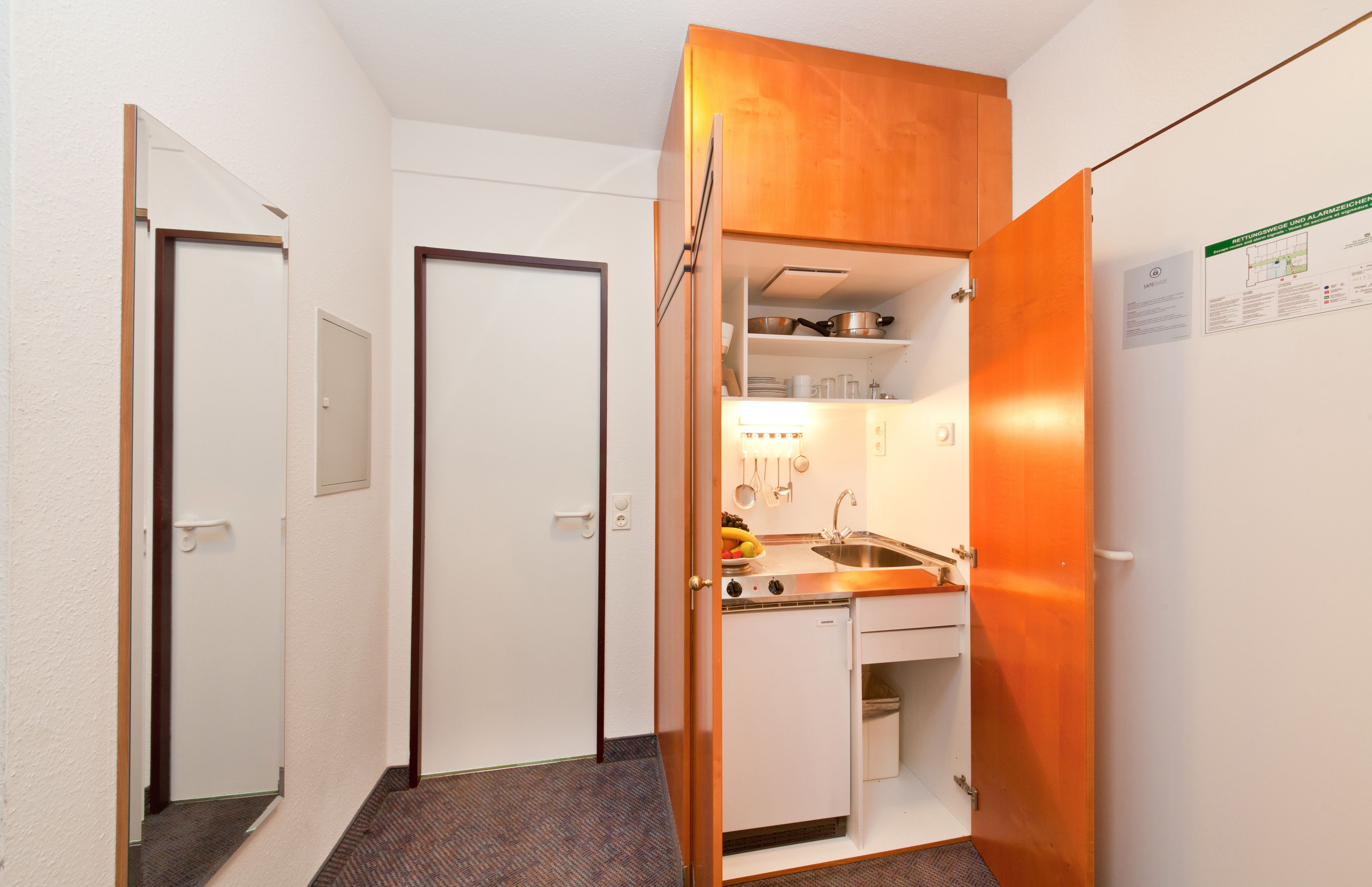 A compact kitchen with a built-in oven, a sink, and a small refrigerator.