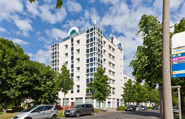 A multi-story hotel with a modern design, featuring a prominent logo on the top. - acora Leipzig Living the City (Leipzig)