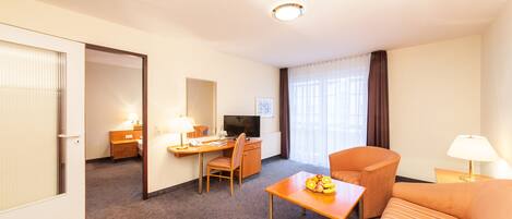 A hotel room with a bed, a desk, a chair, a television, and a window with curtains.