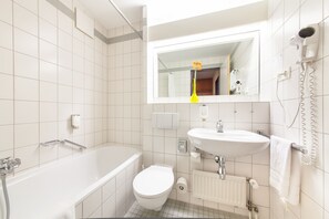 A modern bathroom with a bathtub, toilet, and sink. - acora Leipzig Living the City (Leipzig)
