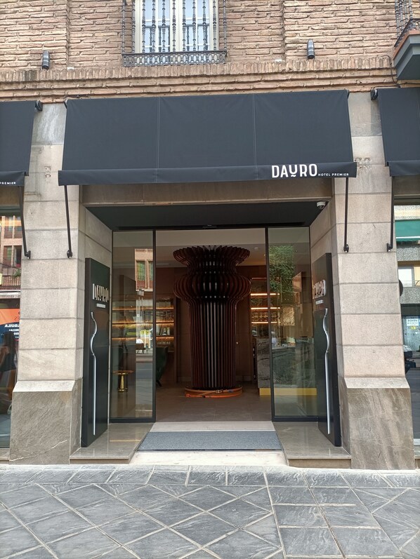 The entrance to a hotel with a modern facade, large glass doors, and a prominent black awning.
