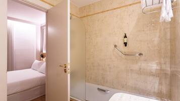 Una habitación de hotel con cama, un baño con bañera y ducha.