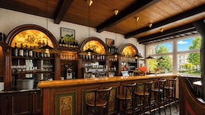 A bar with wooden bar tops, multiple hanging light fixtures, and a view of the outside through large windows. - Hotel Uno Prague (Prague)