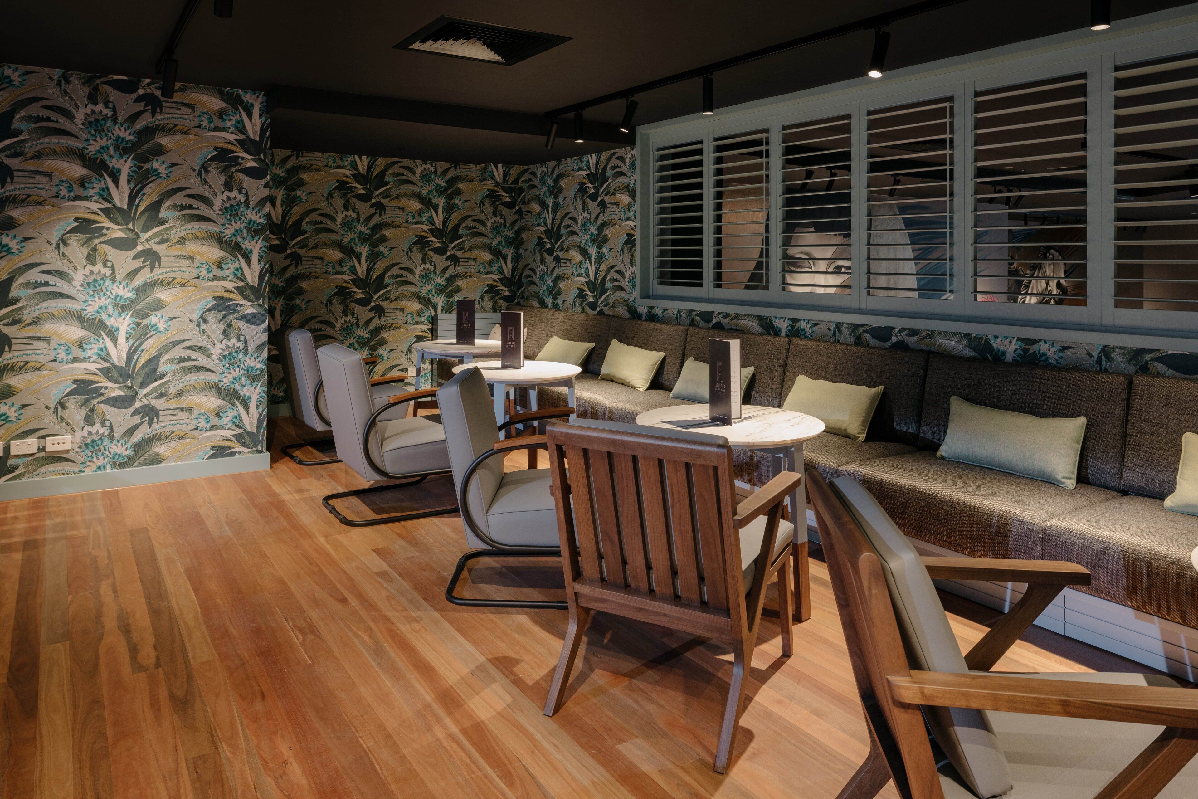 A room with a wooden floor, a sofa, two chairs, and a table.