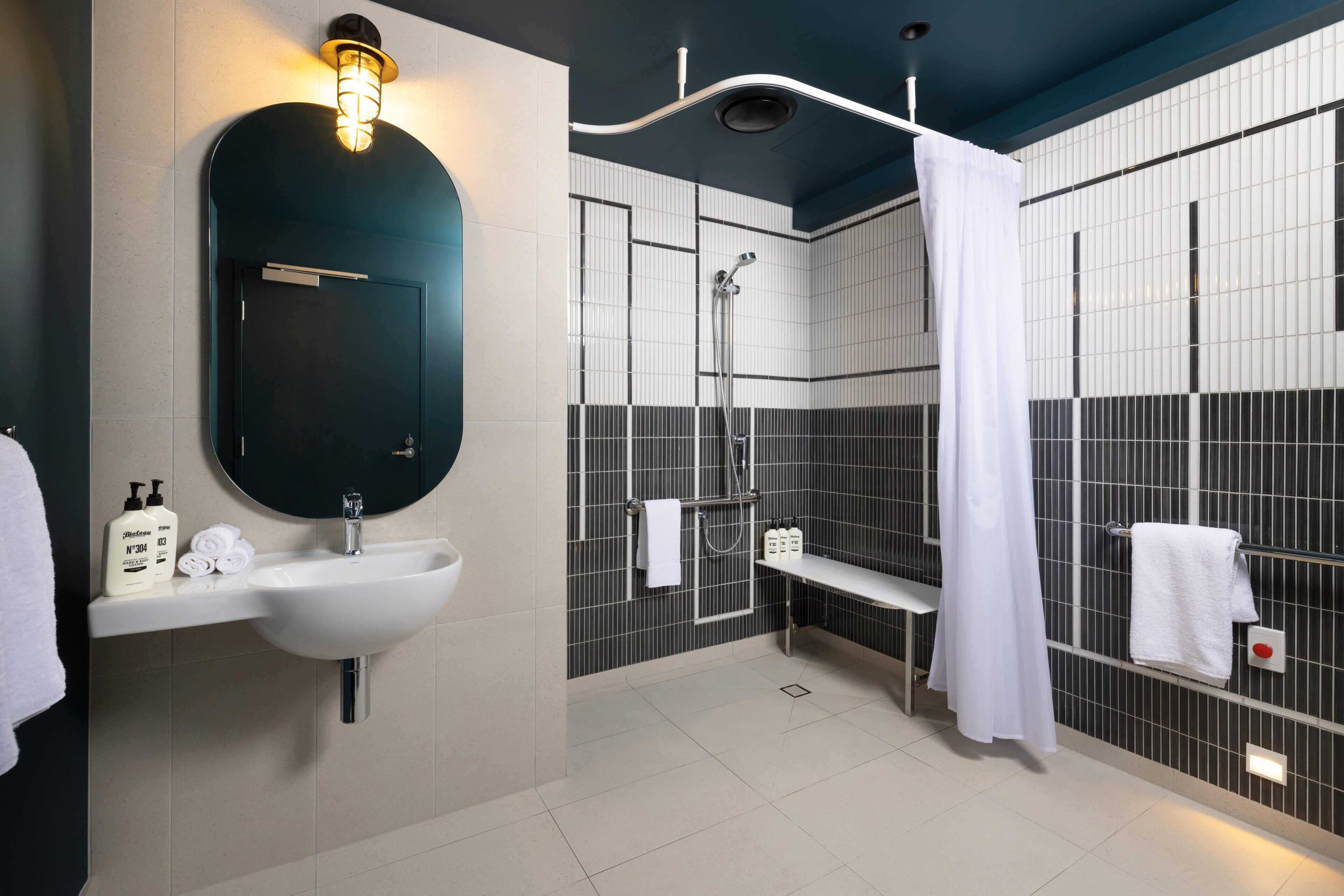 Un baño moderno con lavamanos, espejo y ducha.