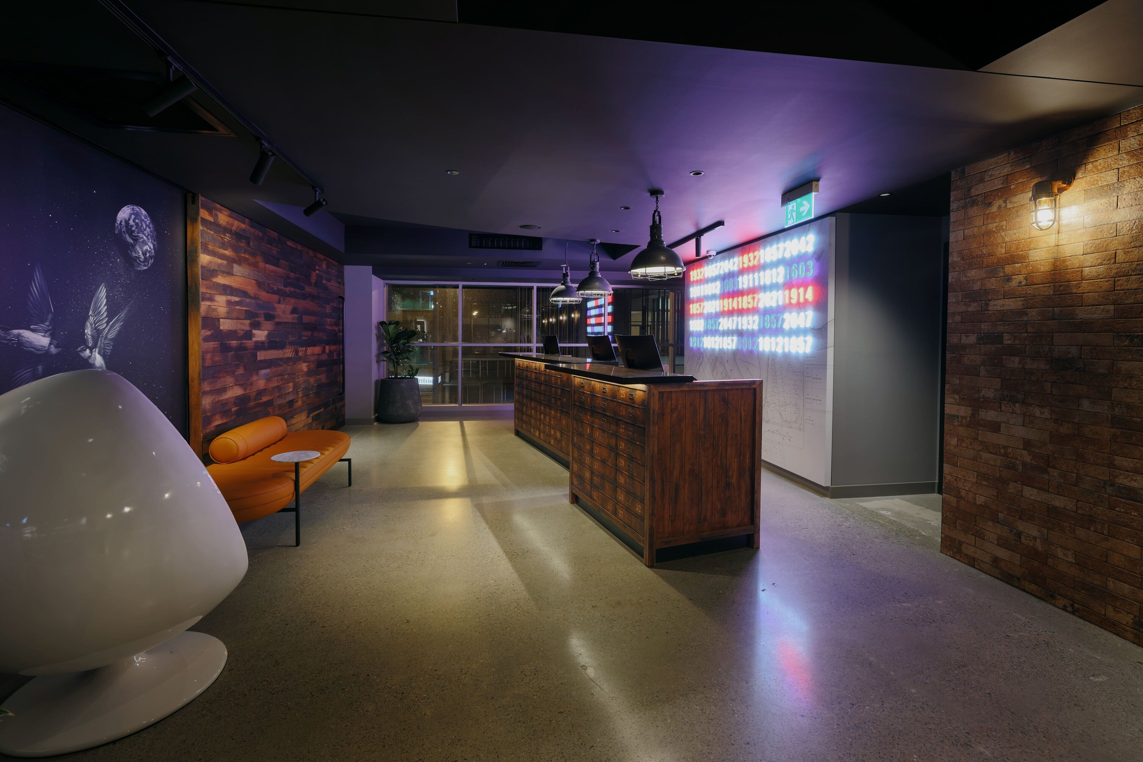 A modern interior with a reception desk, seating area, and a wall with a digital display.