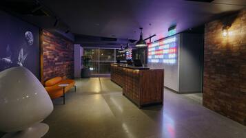 A modern interior with a reception desk, seating area, and a wall with a digital display.