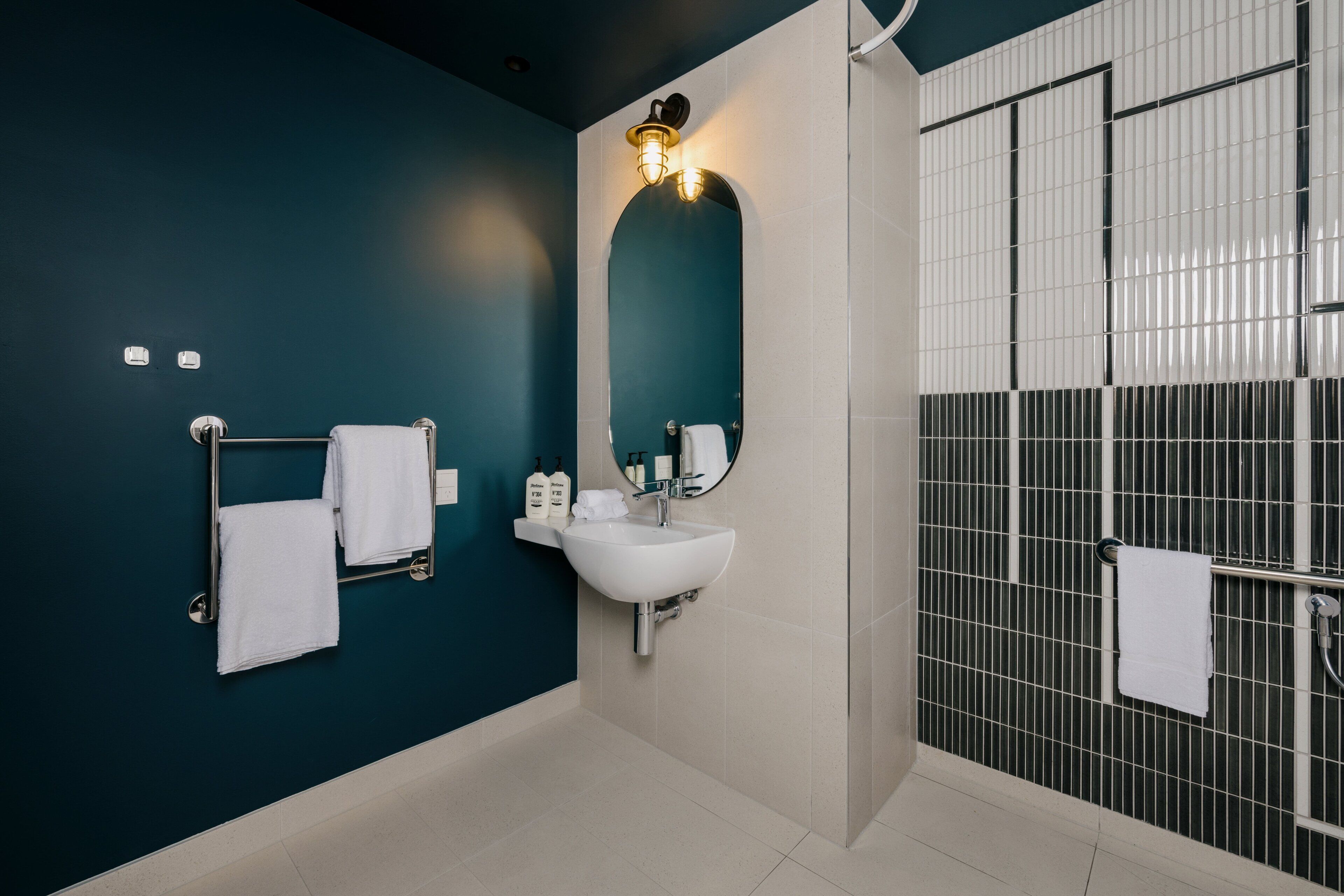Un baño moderno con un lavamanos blanco, un espejo y un perchero para toallas.