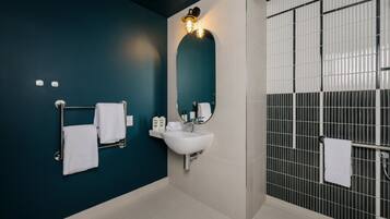 Un baño moderno con un lavamanos blanco, un espejo y un perchero para toallas.