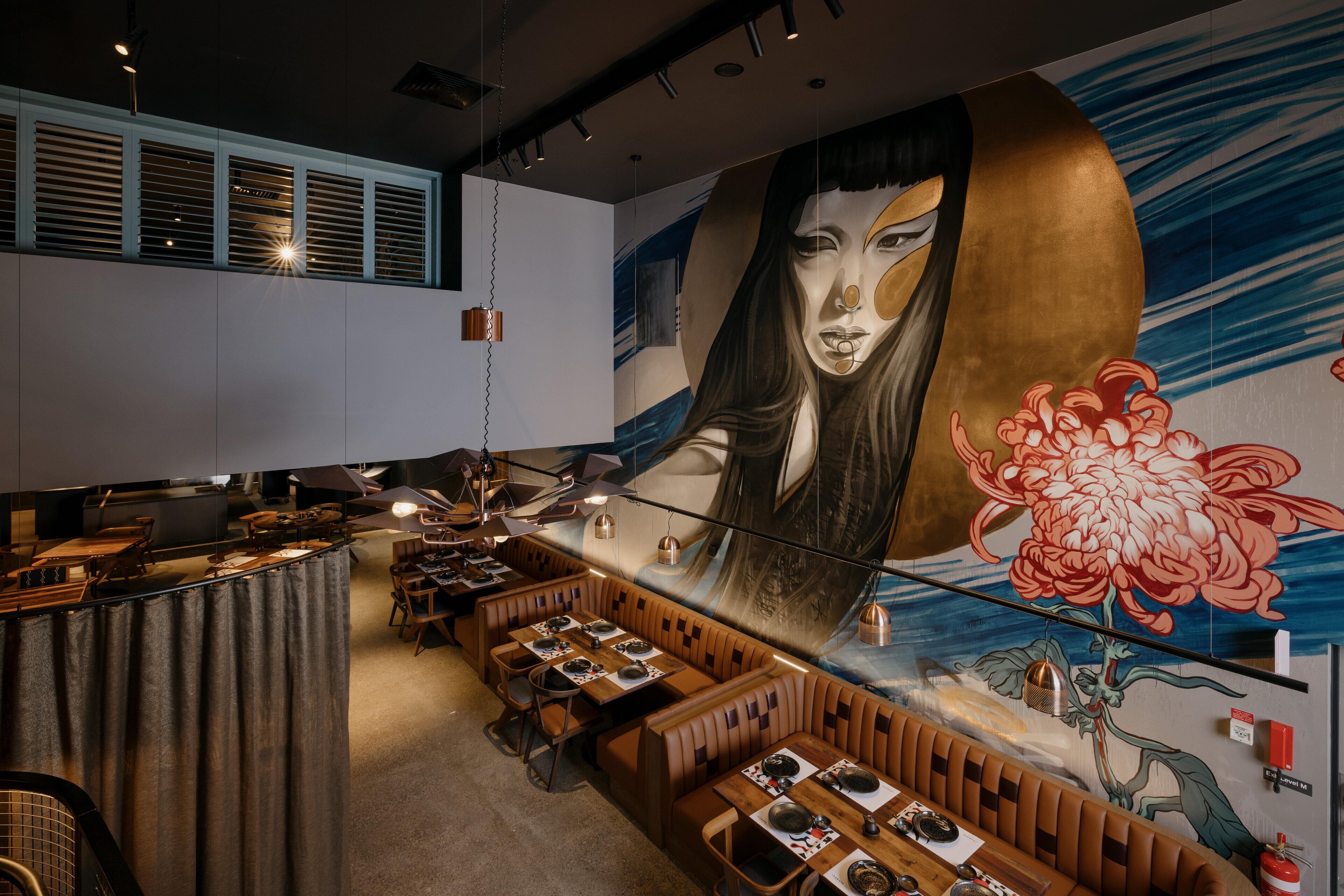 Un restaurante con cabinas y mesas, un mural con una flor grande, y una zona de mostrador.