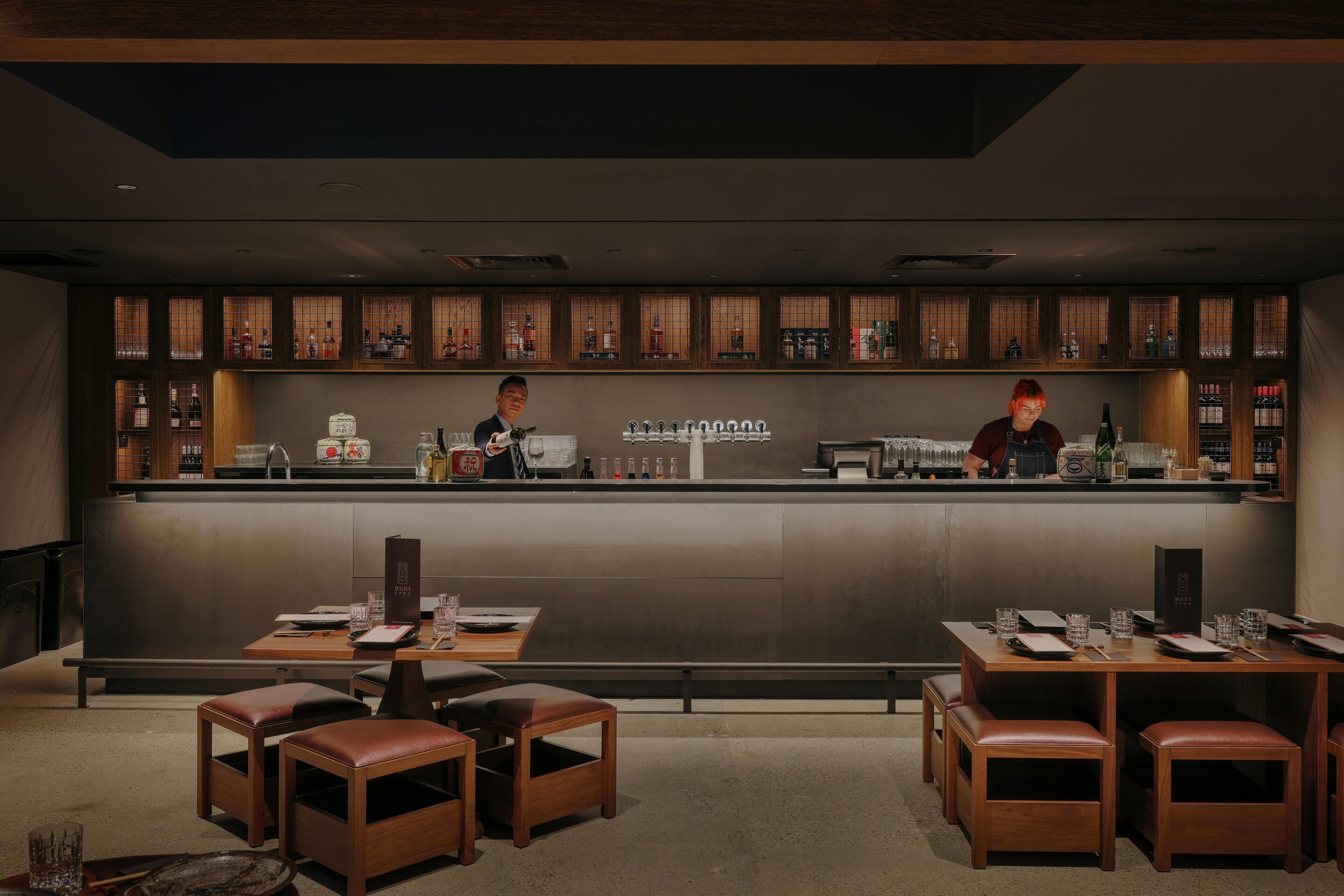 A bar area with a counter, stools, and a seating area with tables.