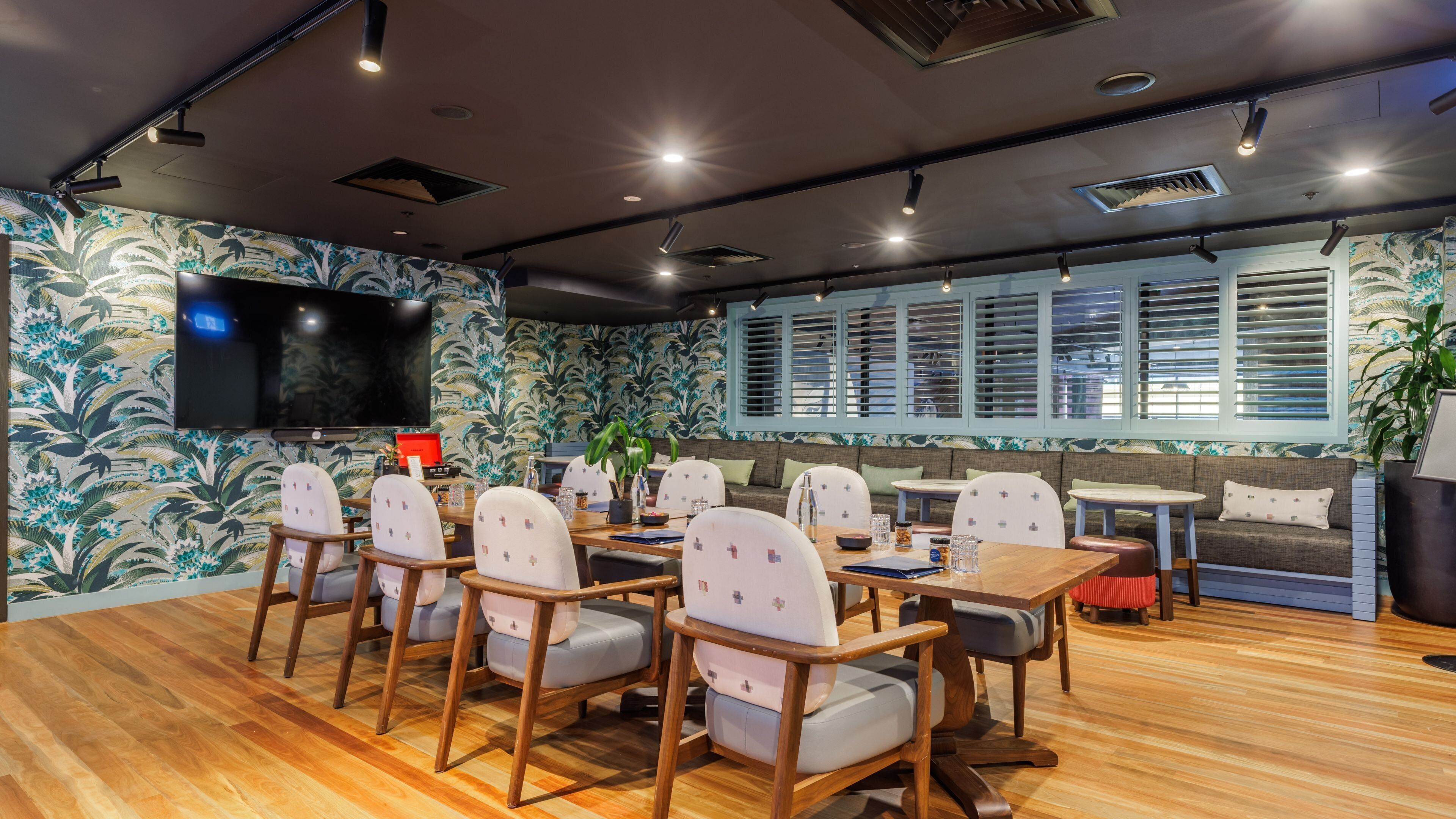 A conference room with a large table, chairs, a television, and patterned wallpaper.