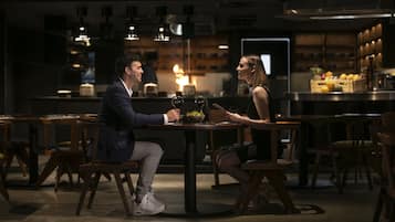 A couple dining in a dimly lit restaurant with wooden furniture and pendant lighting.