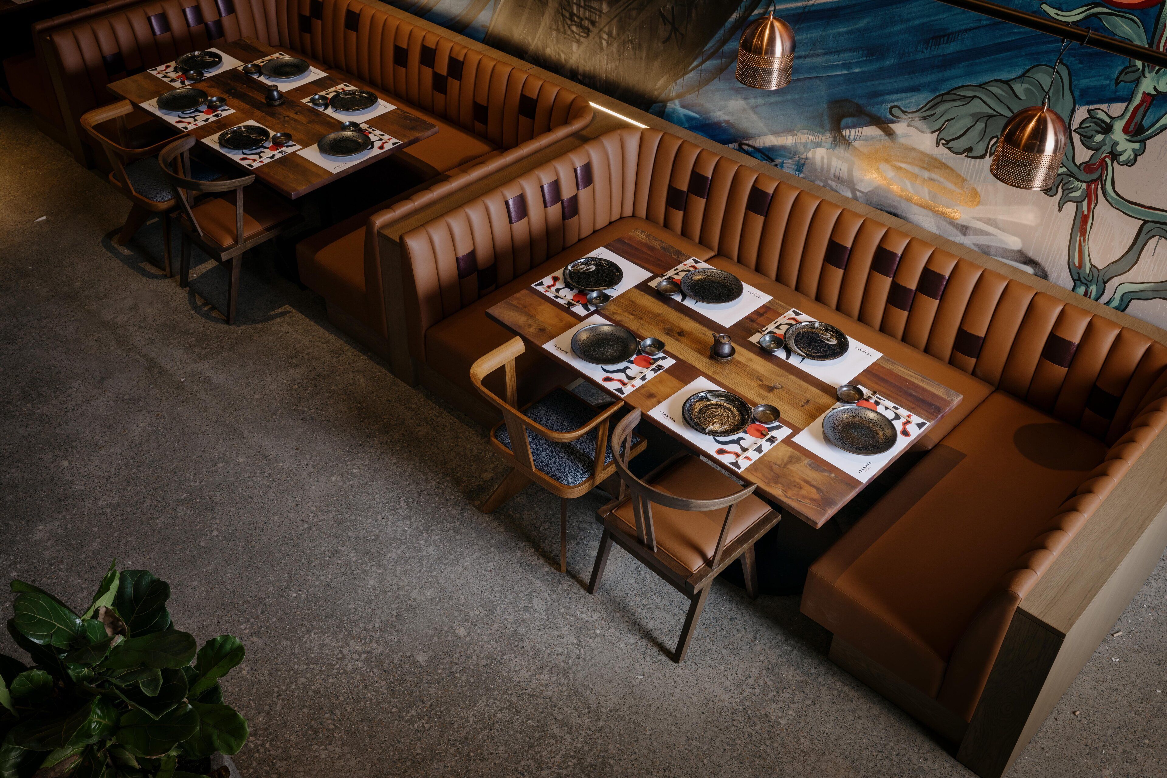 A restaurant with booth seating, wooden tables, and a mural on the wall.