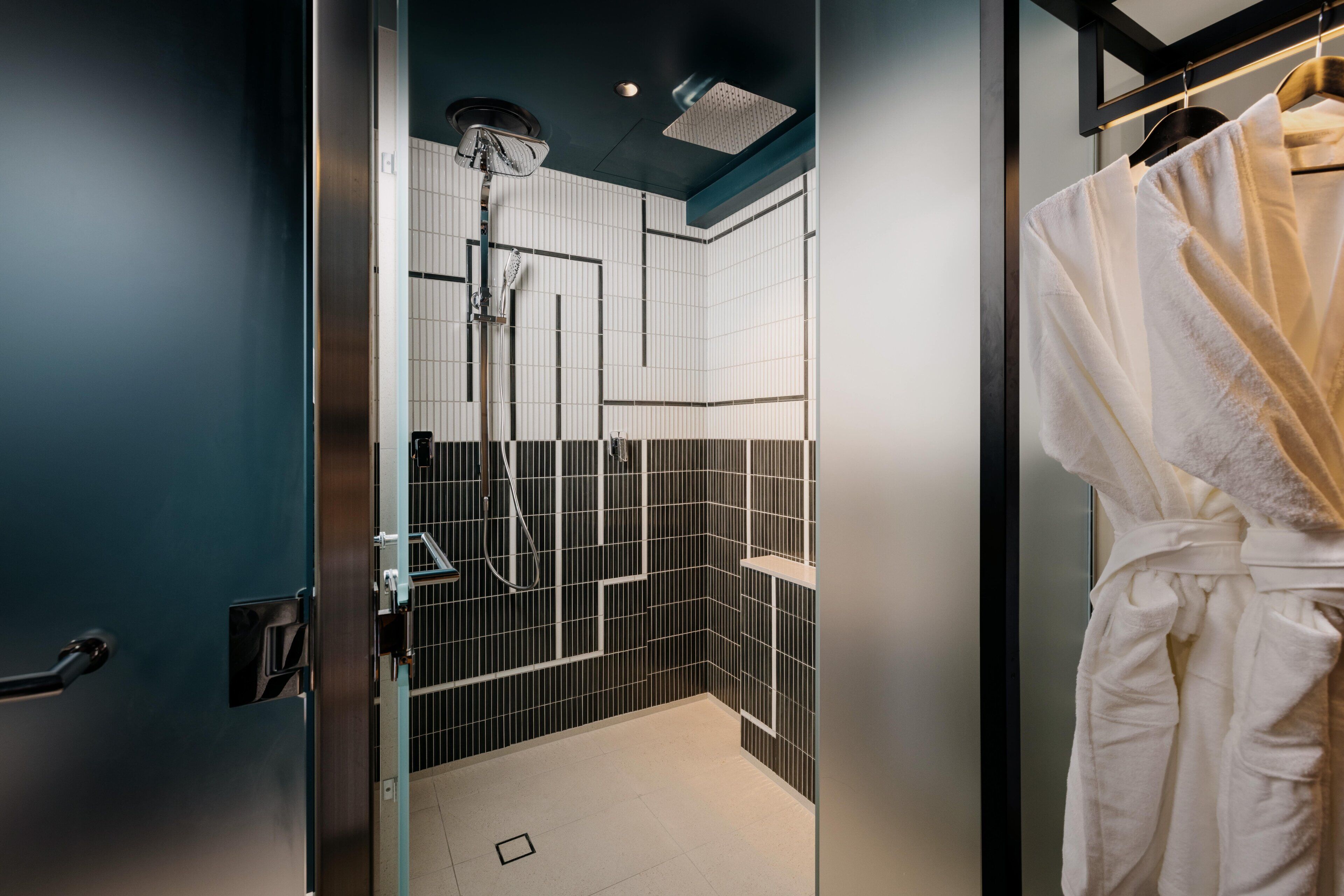 Une salle de bain moderne avec une douche, un porte-serviettes et une porte en verre.