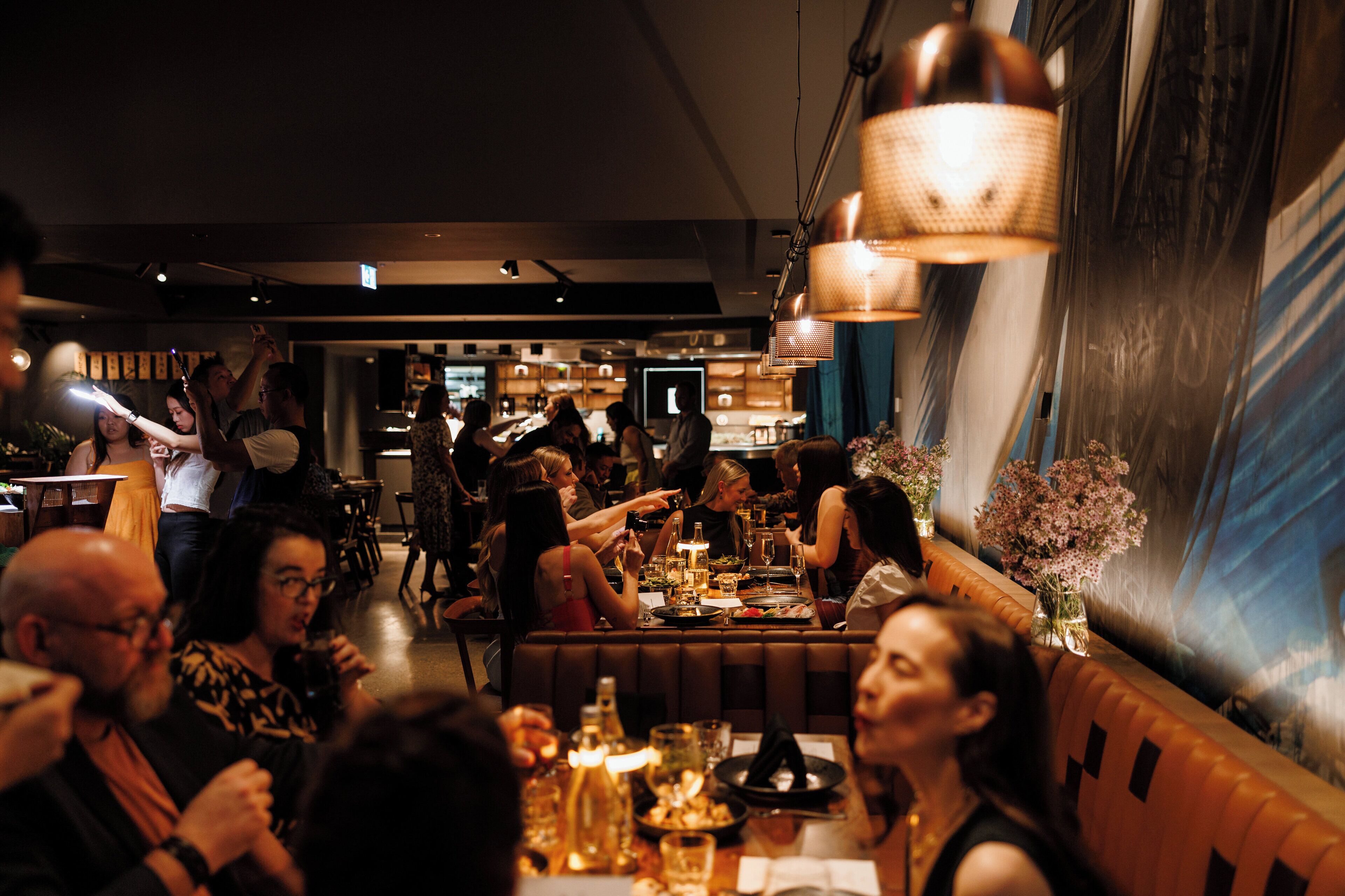 Ein Restaurant mit einem langen Gemeinschaftstisch, Sitzecken und einer Bar.