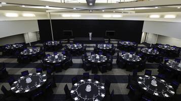 Un salón de conferencias con varias mesas redondas, cada una con sillas y centros de mesa.