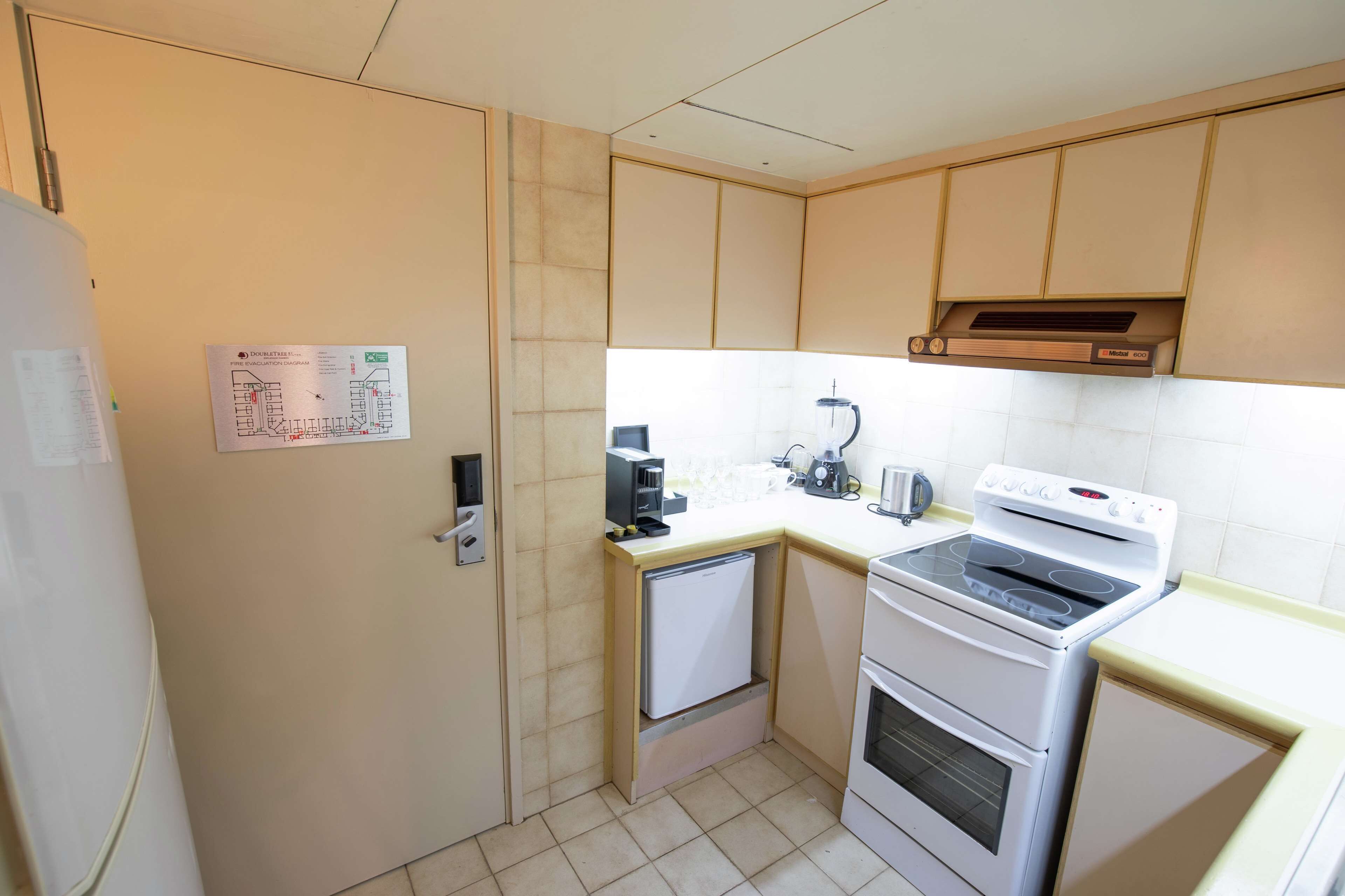 Una cocina compacta equipada con refrigerador, microondas, estufa y un lavamanos pequeño.
