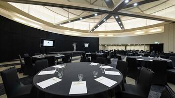 A conference room with round tables, black chairs, and a large screen.