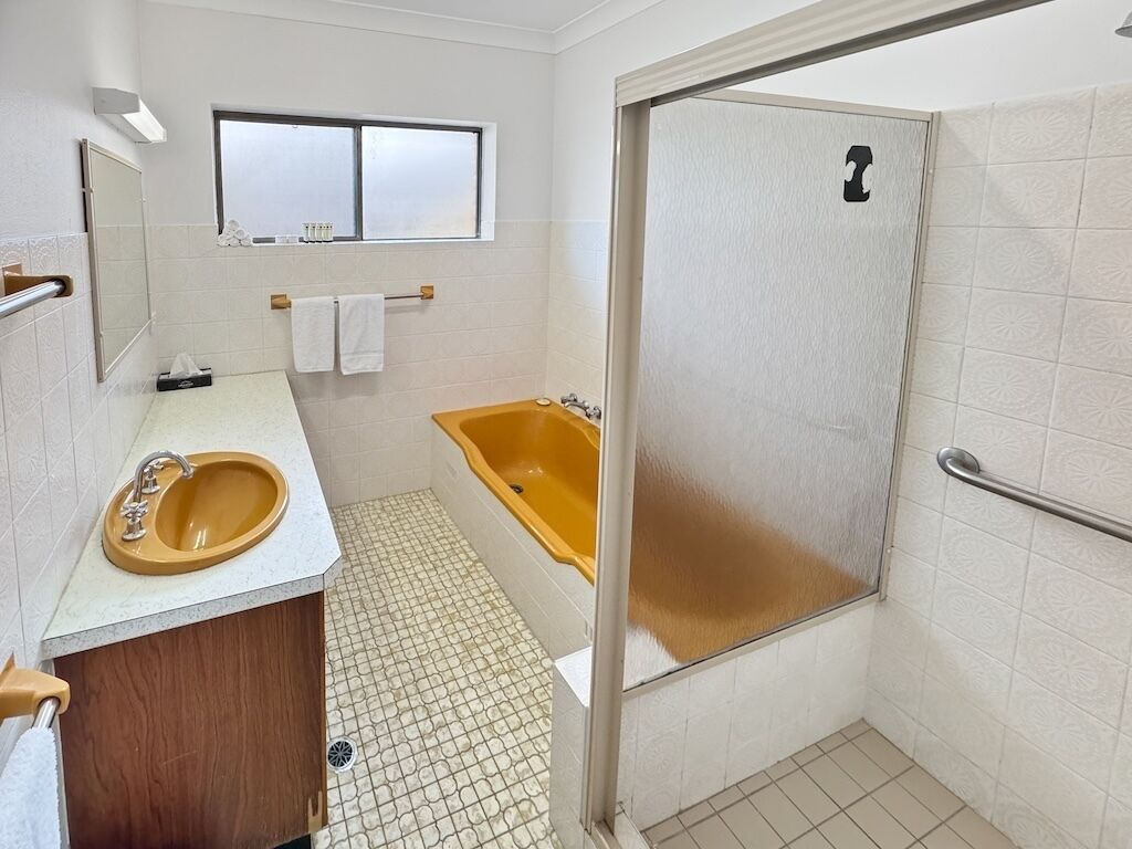 Un baño con lavamanos, espejo, toallero y bañera.