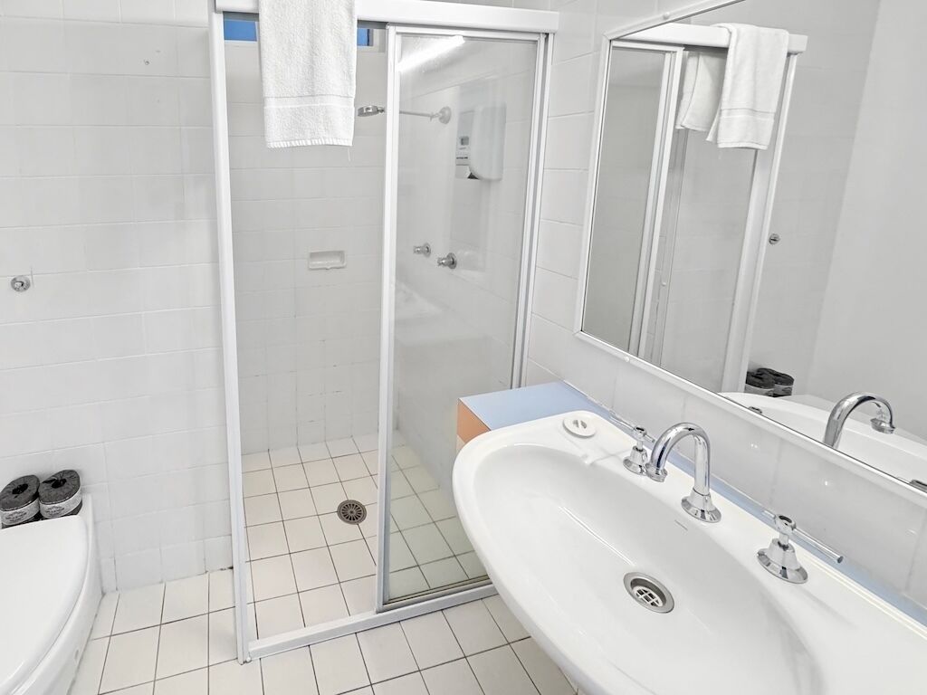 A bathroom with a shower, a sink, and a mirror.
