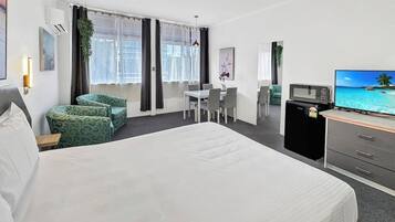 Hotelkamer met een groot bed, een bureau met stoel, een televisie en uitzicht op de oceaan.