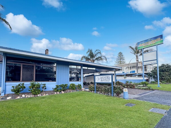 A motel with a reception area, a sign indicating the motel entry, and a sign for the Golden Sands Motel.
