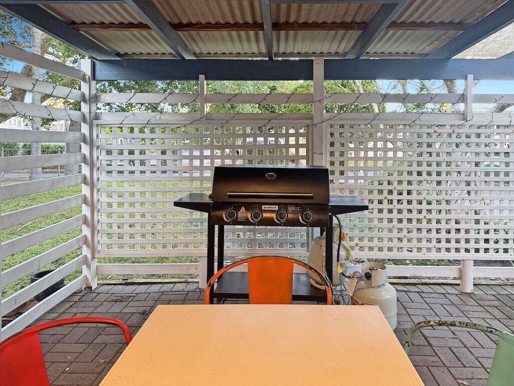 Une terrasse extérieure avec un barbecue, une table et des chaises.