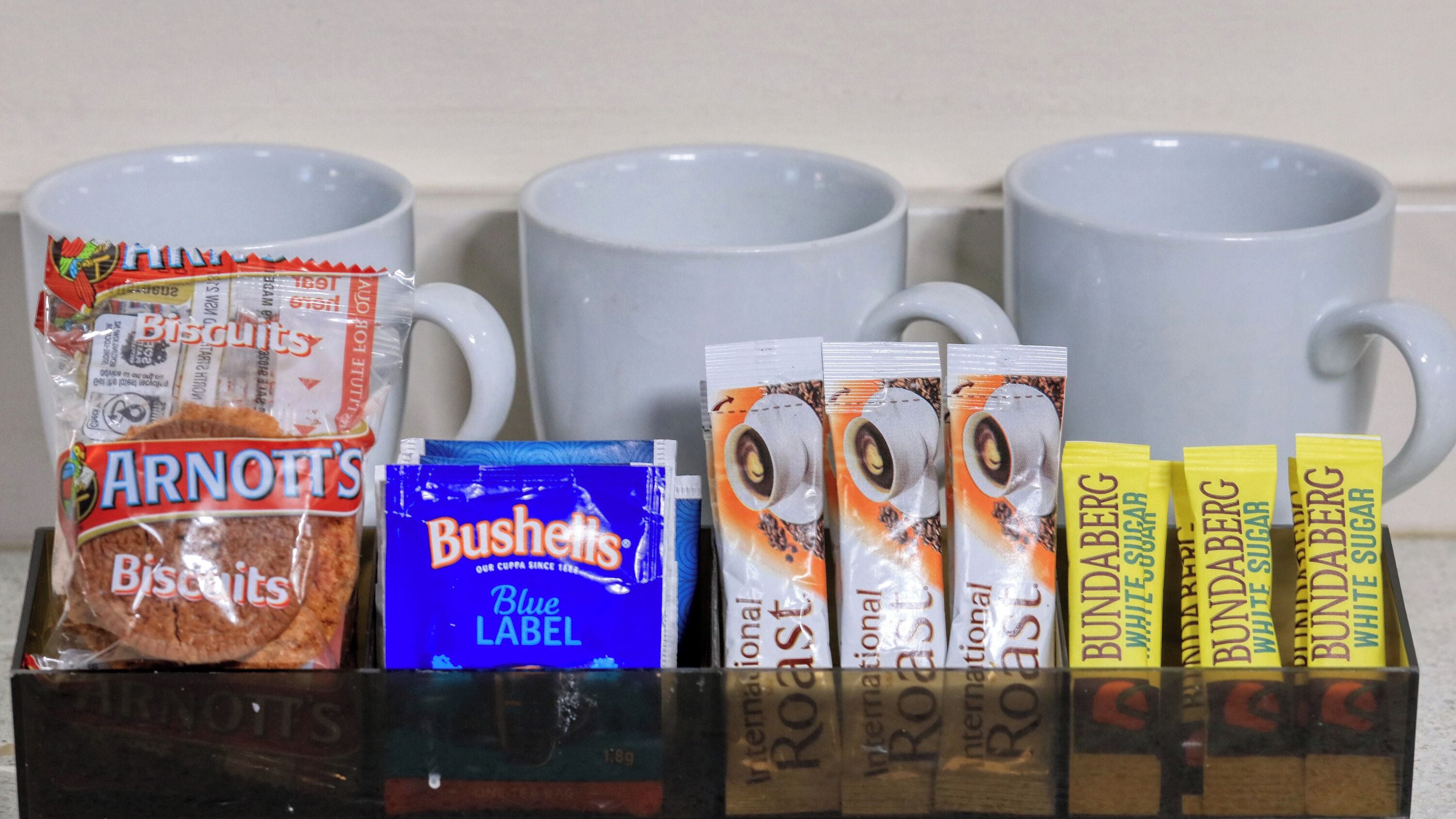 Variedad de aperitivos y productos de café frente a tazas blancas.
