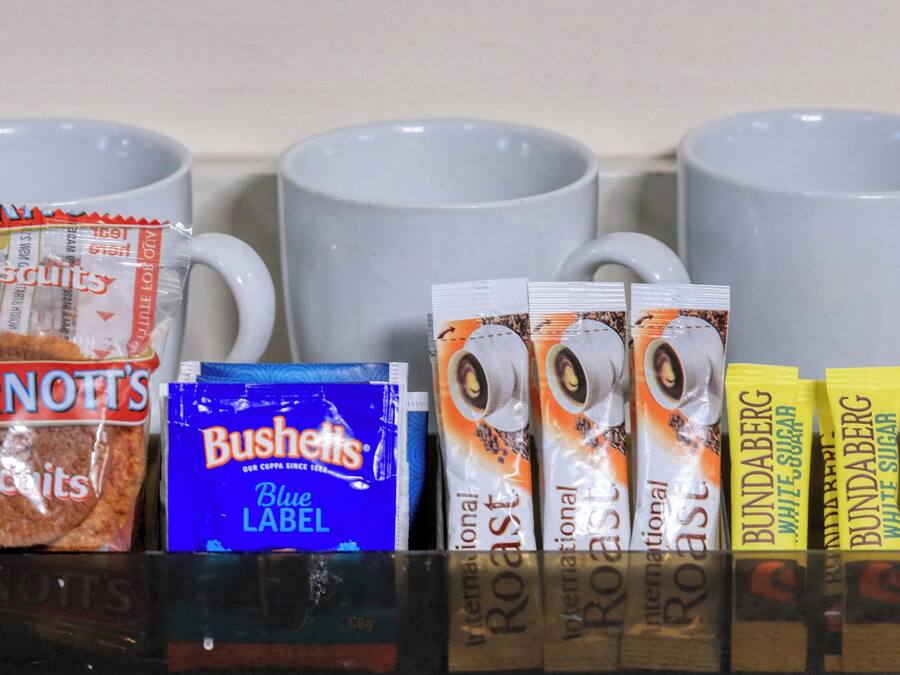 Variedad de aperitivos y productos de café frente a tazas blancas.