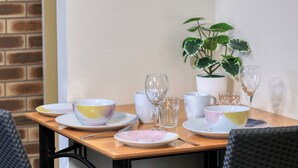 A dining table set with various bowls, glasses, and a potted plant. - Top Of The Town Motel (Inverell)