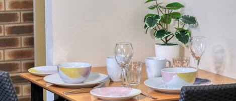 Una mesa de comedor dispuesta con diferentes cuencos, vasos y una planta en maceta.