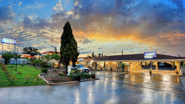 A motel with a large sign, a parking lot, and a well-maintained lawn. - Top Of The Town Motel (Inverell)