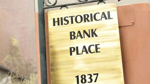 Un cartel con la inscripción 'Historical Bank Place 1837' sujeto a un poste metálico.