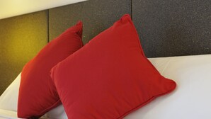 Una cama con dos almohadas rojas y un colchón blanco.