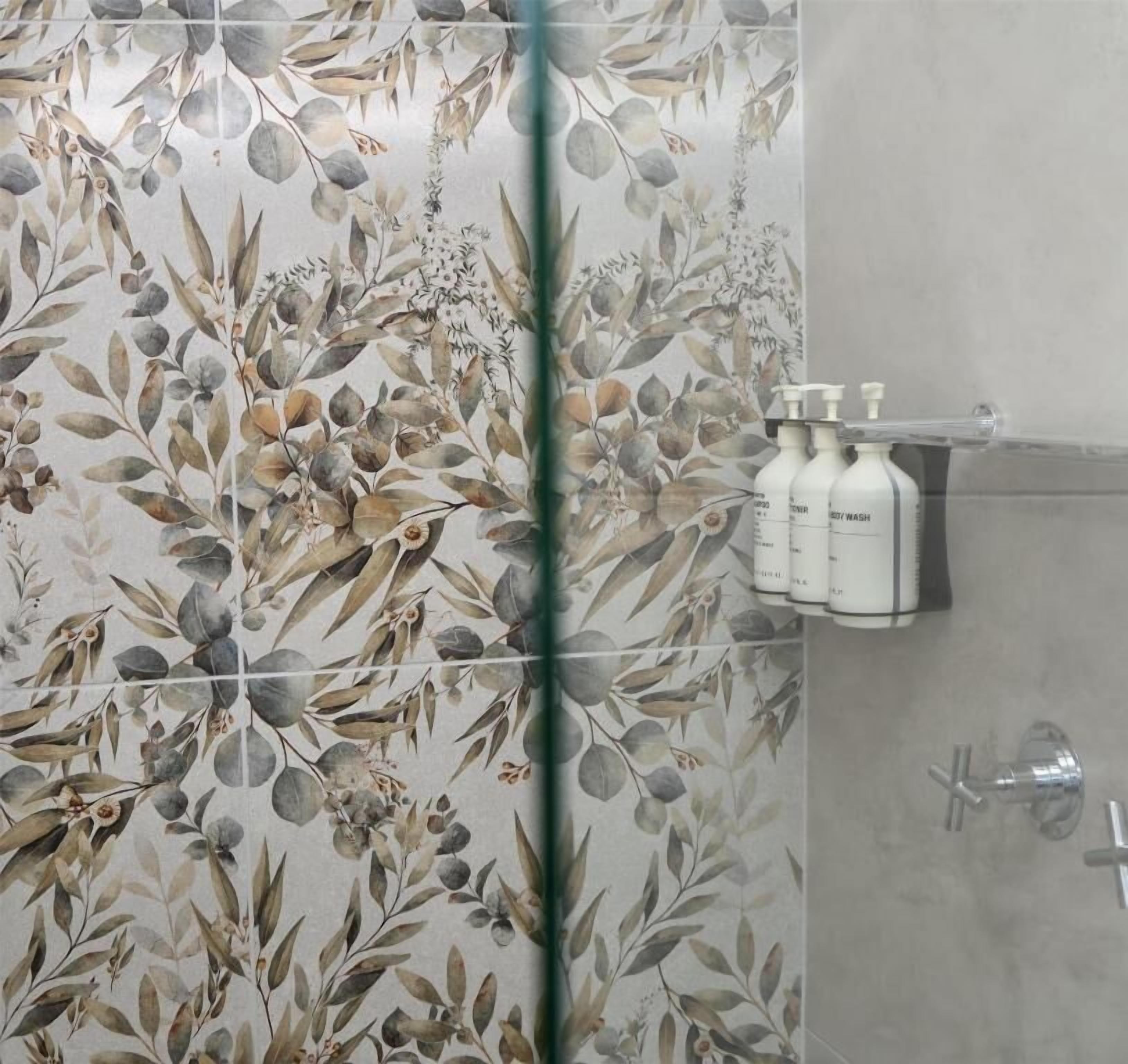 Un baño con diseño de papel tapiz floral, una zona de ducha y un estante con artículos de aseo.