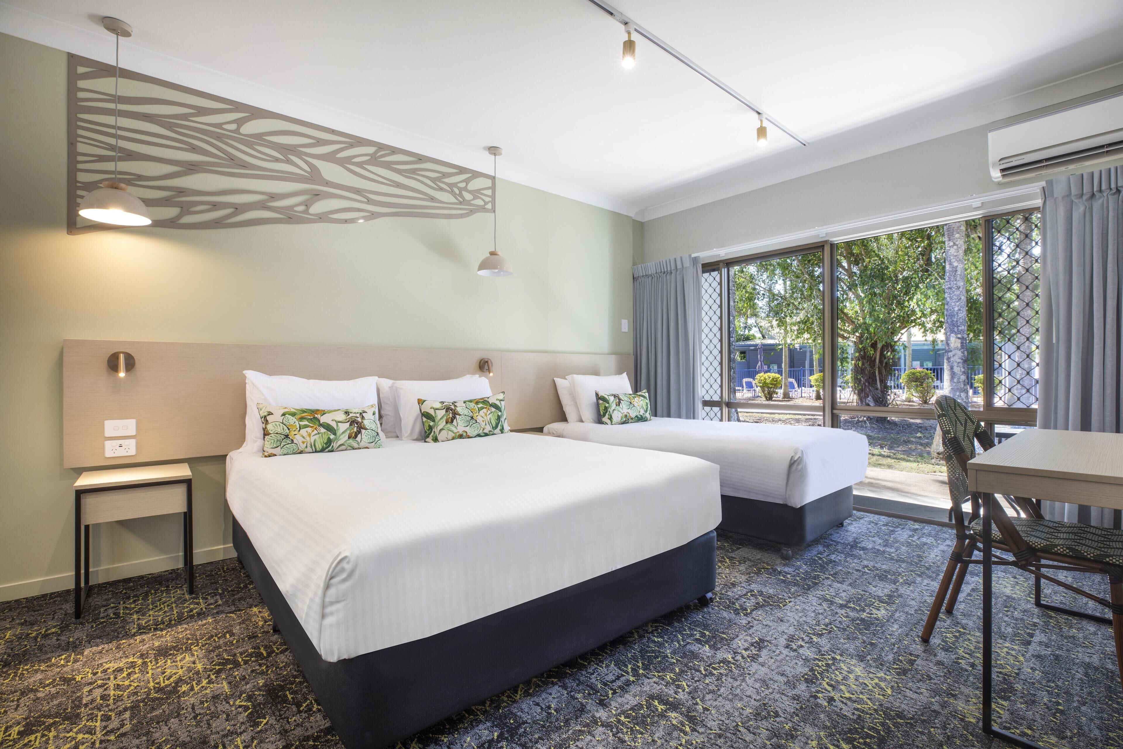 Une chambre d’hôtel avec deux lits, une petite table, une chaise et une vue sur l’extérieur.