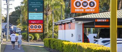 A hotel sign with amenities and a drive entry sign.