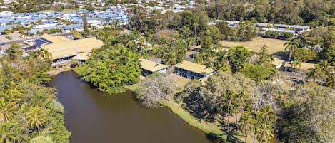 An aerial view of a residential area with houses, a river, and a distant coastline.