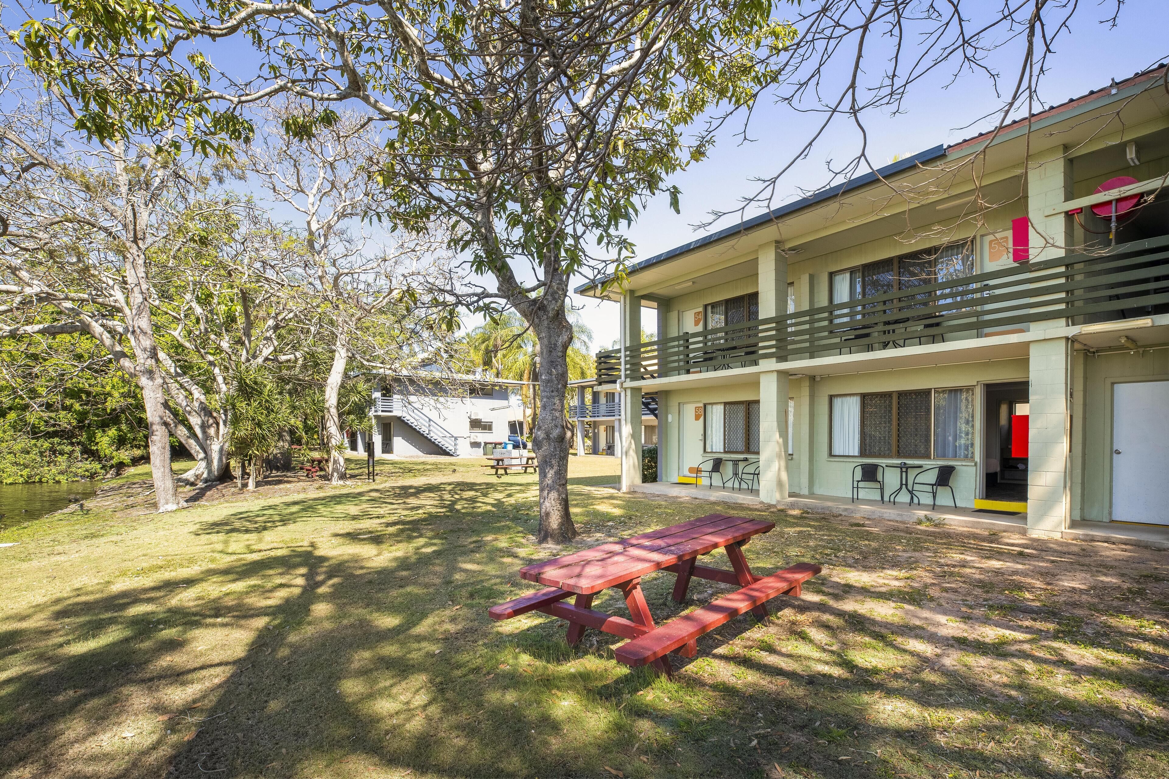 A two-story building with a balcony, a picnic table, and a small outdoor seating area.