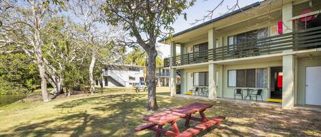 A two-story building with a balcony, a picnic table, and a small outdoor seating area.