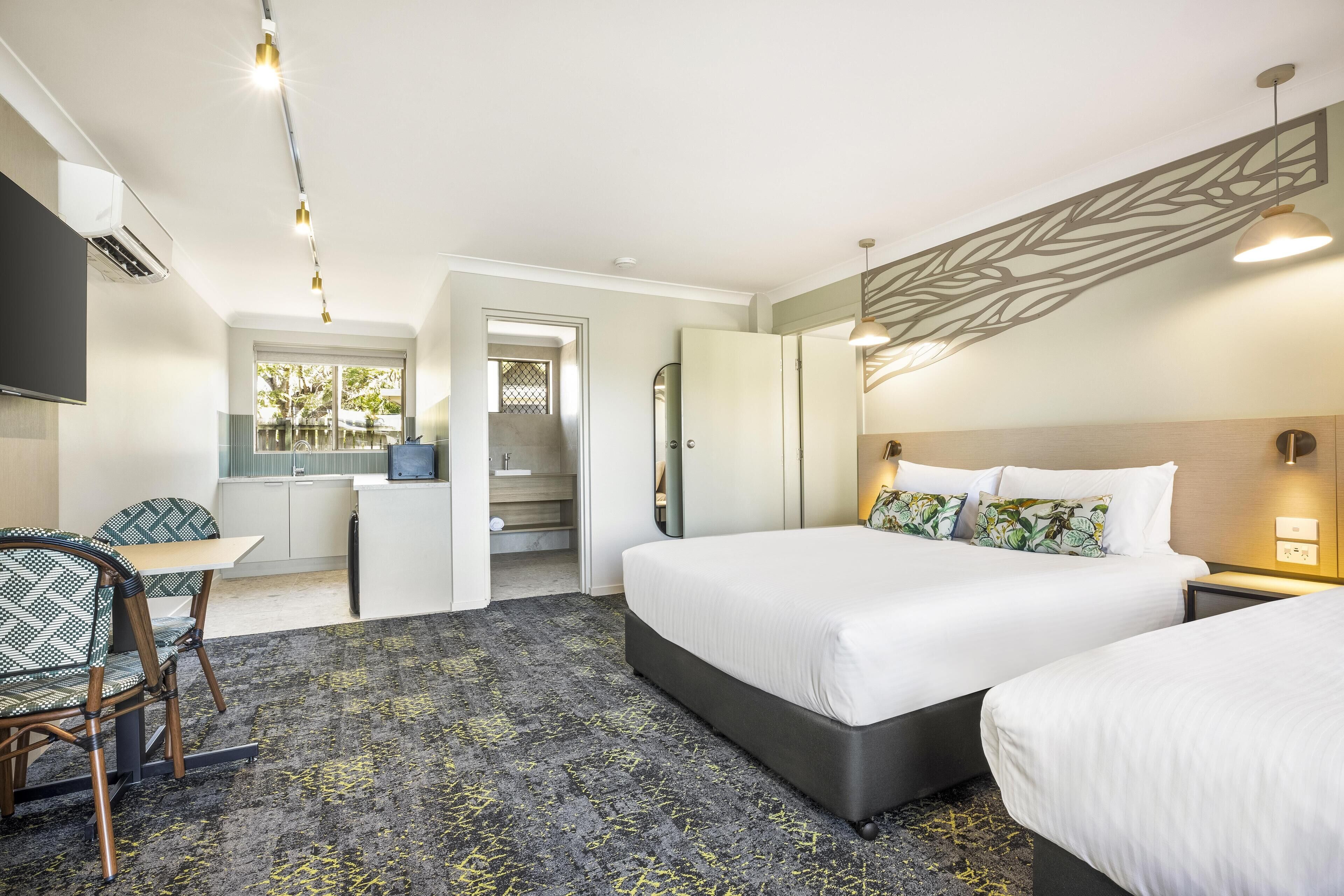 A hotel room with a bed, a desk, a chair, and a bathroom.