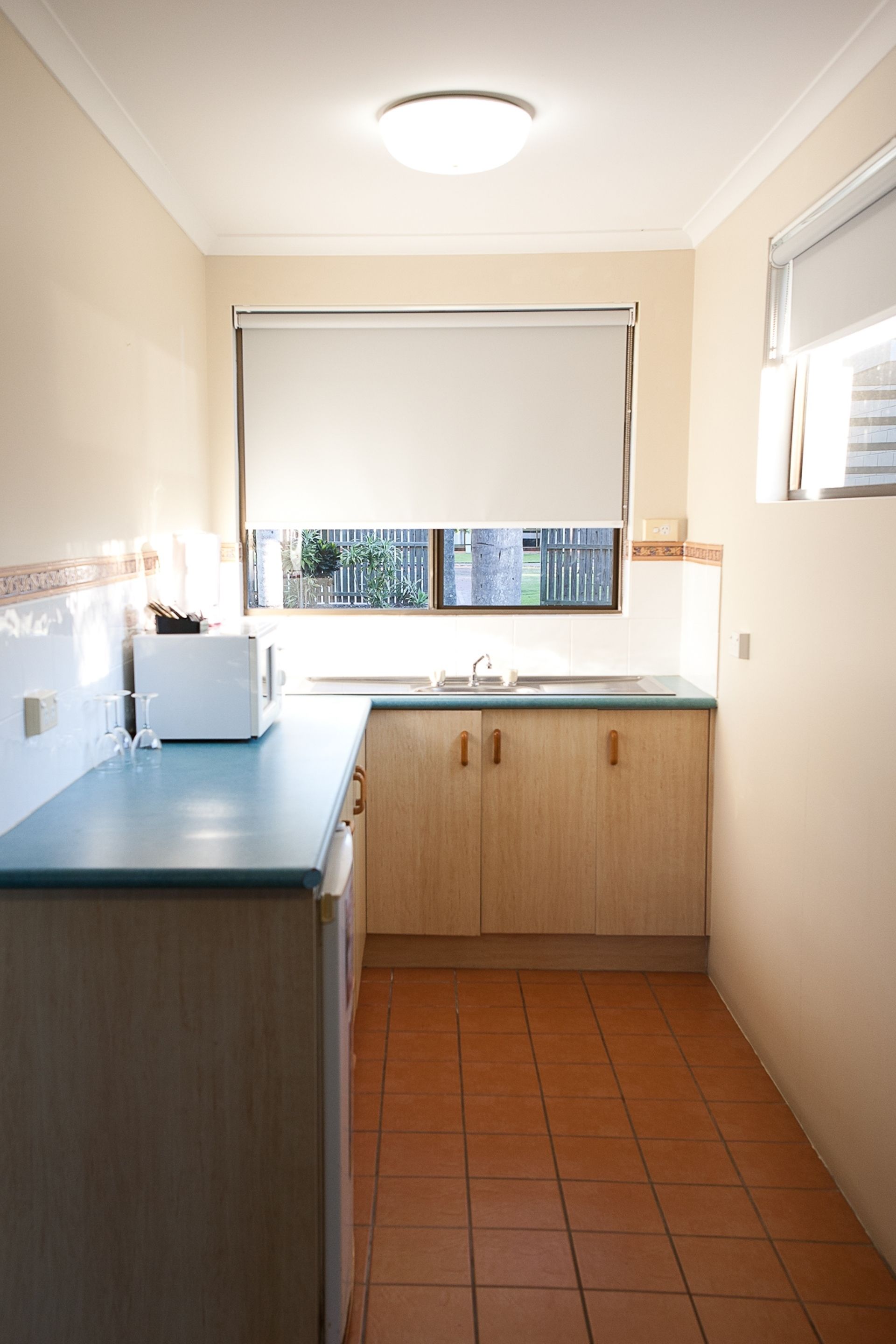 A compact kitchen with a window, a microwave, and a sink.