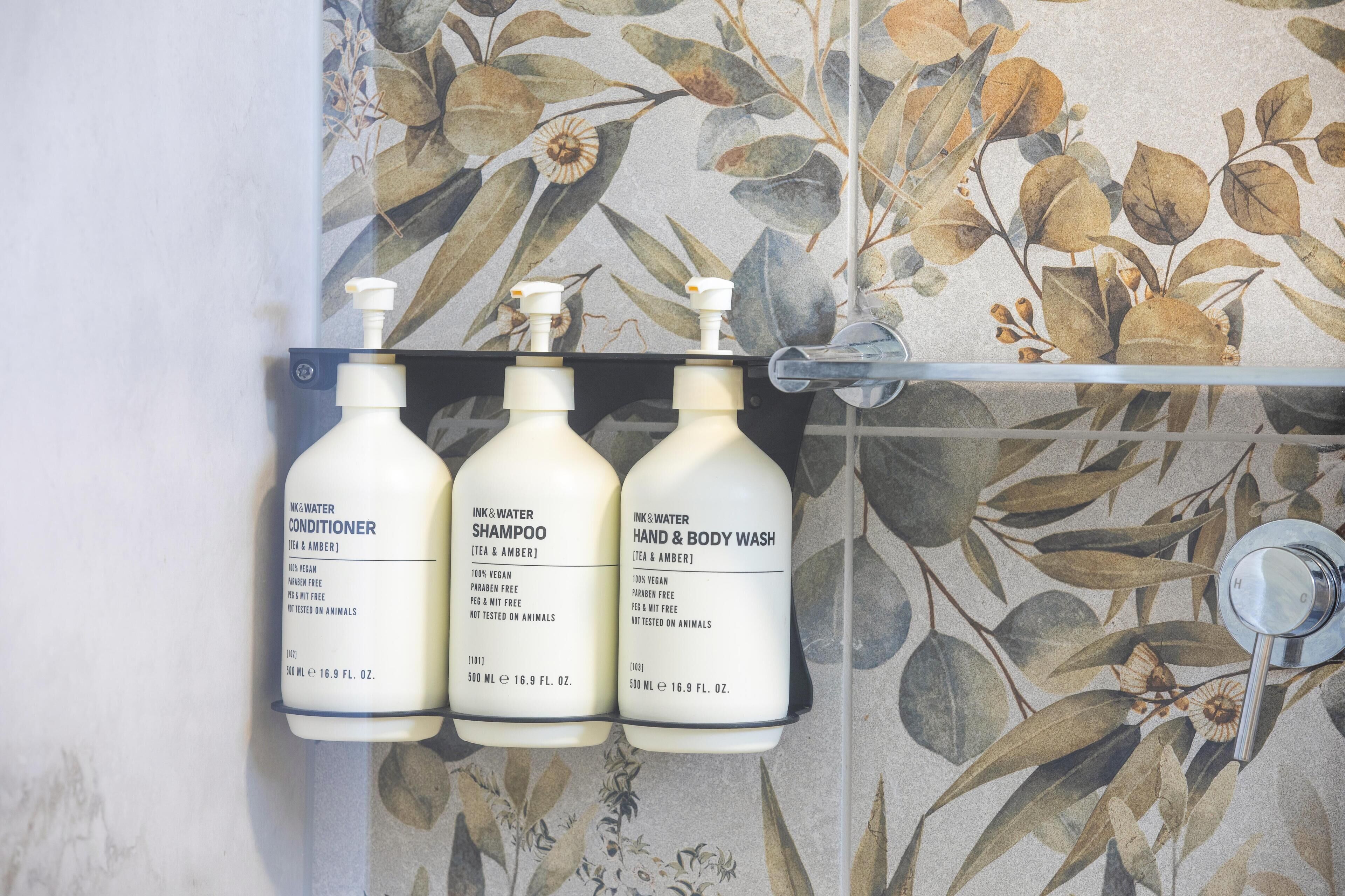 Three bottles of personal care products on a bathroom shelf.
