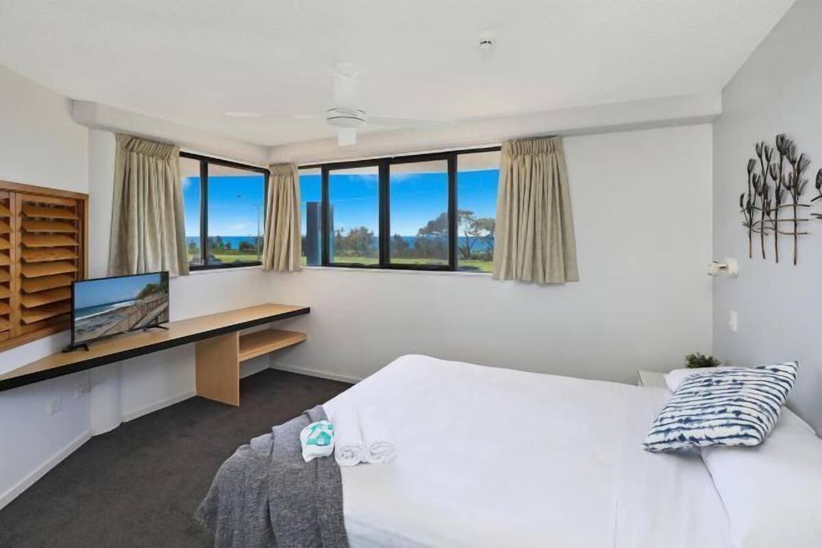 Une chambre d’hôtel comprenant un lit, un bureau avec un téléviseur à écran plat, une fenêtre avec vue et un ventilateur de plafond.