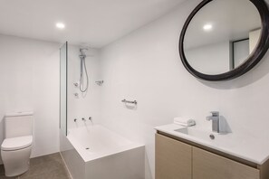 A modern bathroom with a toilet, a shower, and a sink.
