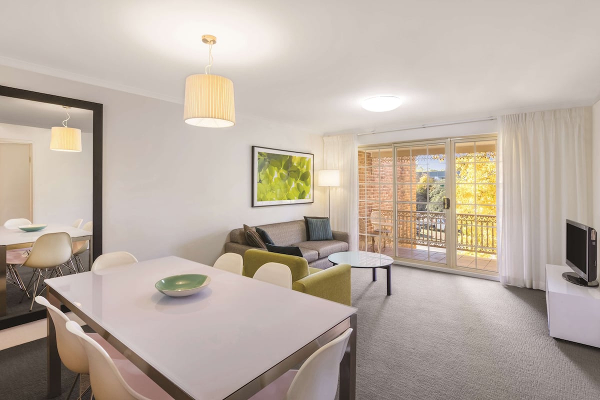Ein modernes Wohnzimmer mit Essbereich, einer Couch, einem Fernseher und einem Balkon mit Blick.