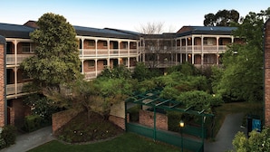 A courtyard with a brick building, a pergola, and a pathway. -  Kingston Gardens Serviced Apartments  (Griffith)