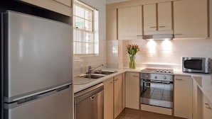 A modern kitchen with stainless steel appliances, a built-in oven, and a microwave. -  Kingston Gardens Serviced Apartments  (Griffith)
